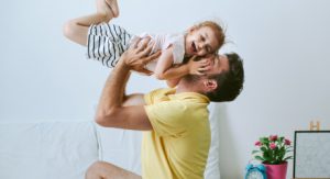 Dad holding young daughter up in the air - pediatric dentistry
